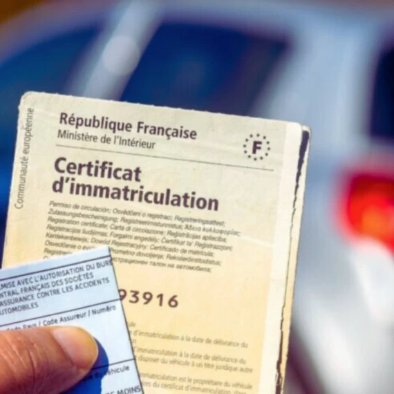 Une personne tient un certificat d'immatriculation français (carte grise) et une carte d'assurance devant une voiture floue en arrière-plan. Le document officiel affiche le logo de la République Française et du Ministère de l'Intérieur.